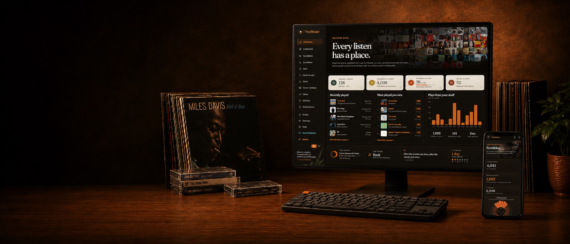 VinylScape on a desktop monitor and phone on a warm wooden desk, beside a row of vinyl records